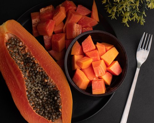 Sliced ripe papaya and mango served on a minimalist ceramic plate